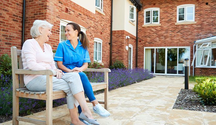 A caregiver and a senior woman sitting on a wooden bench