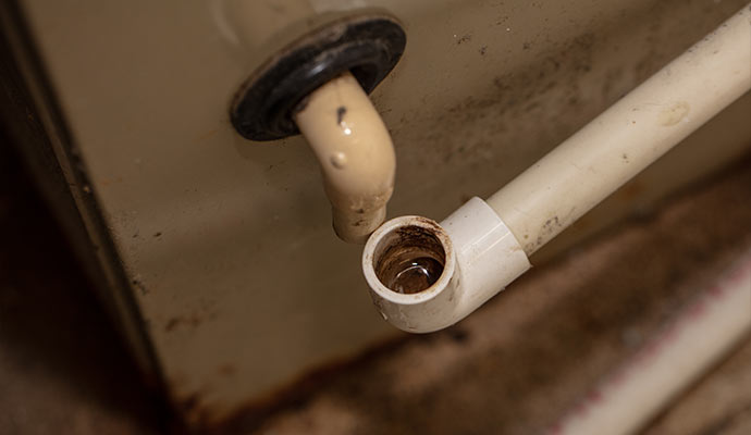 A close-up view of a disconnected PVC condensate drain line