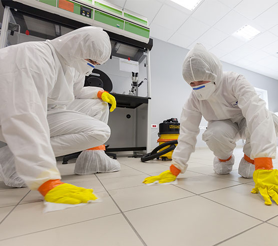 Professional team with hazmat suits performing hand-sanitization of a tiled floor