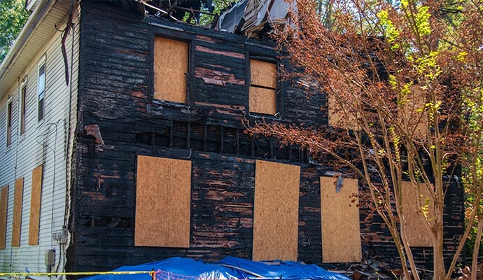 Charred house exterior with boarded up windows