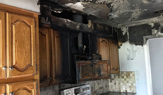 Charred kitchen microwave and soot covered cabinets