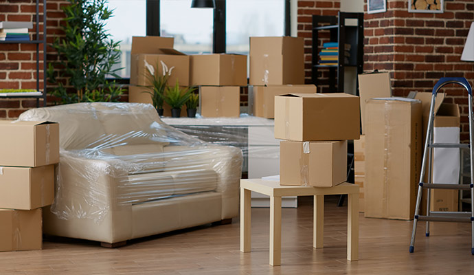 Plastic wrapped sofa and cardboard boxes in living room