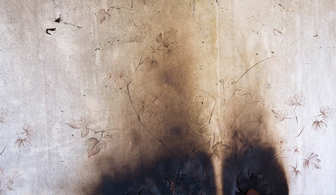 Smoke-damaged drywall and wallpaper