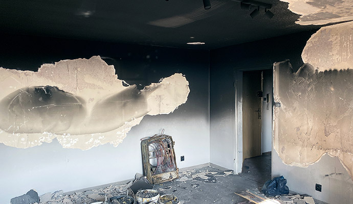 Soot covered room with peeling plaster and burnt electrical panel