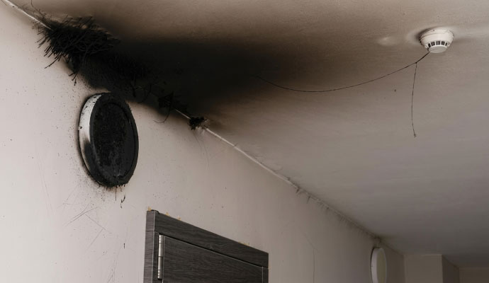 Soot stain on ceiling near charred fixture and smoke detector