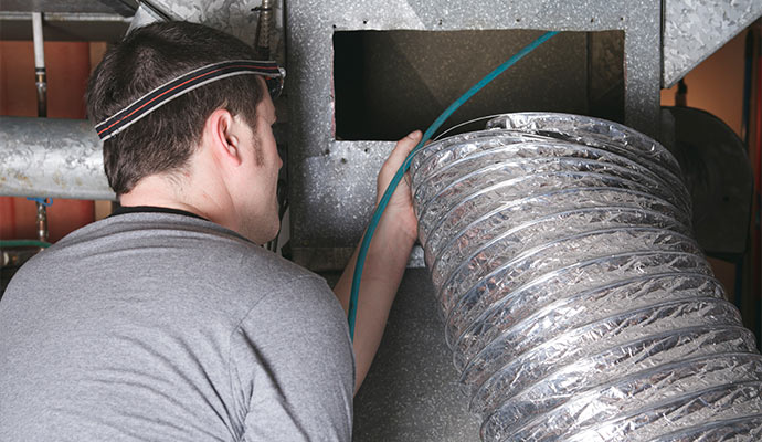 Technician cleaning a air duct.