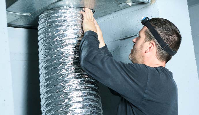Technician inspecting and cleaning a flexible air duct