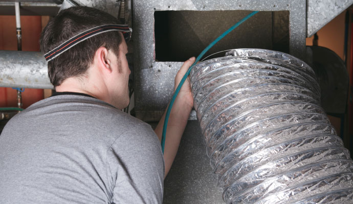 Technician holding dusty flexible air duct for HVAC cleaning