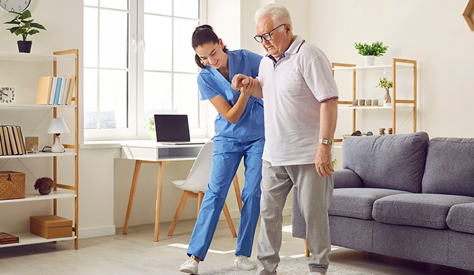 Helping a senior man walk in the living room