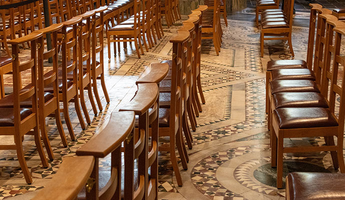 Rows of wooden chairs with leather seats arranged on a church