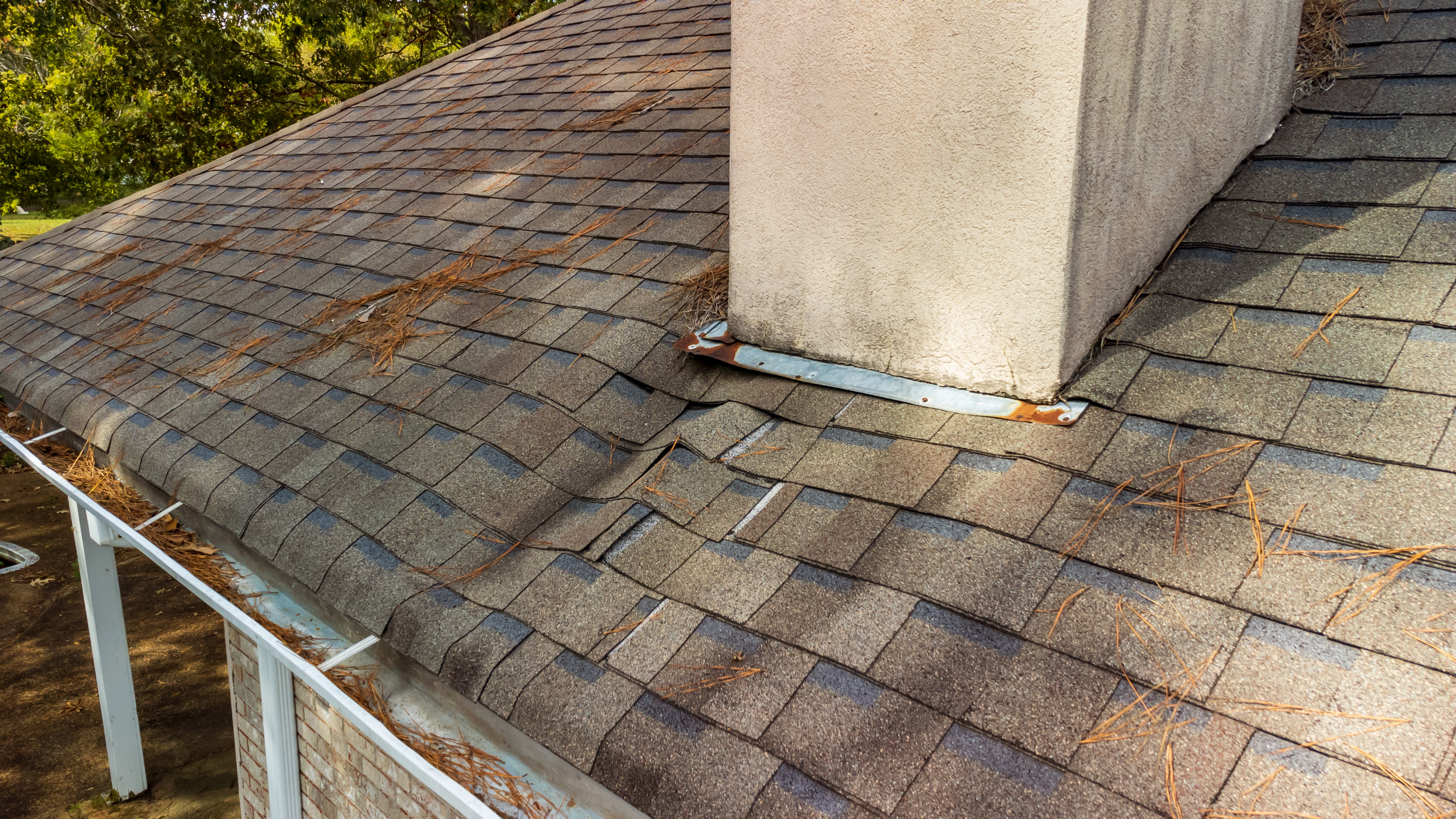 Damaged roof shingles and chimney flashing