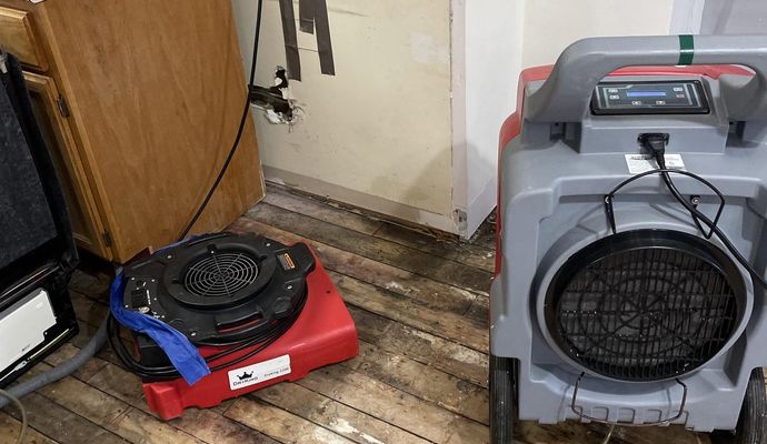 Industrial air movers and dehumidifiers used by Cousin Restoration to dry a water-damaged kitchen floor