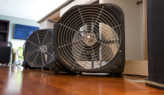Air movers drying water damage on a wooden floor