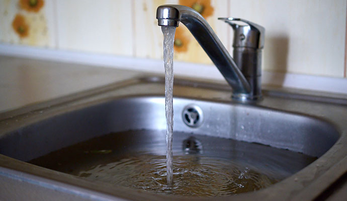 Close-up of a kitchen sink overflowing with water.