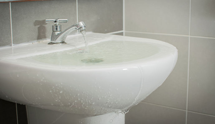 Bathroom sink overflowing with water.