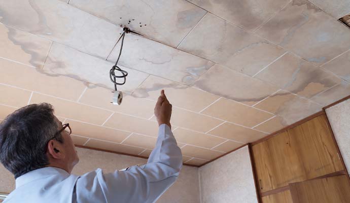 Restoration technician inspecting ceiling water damage