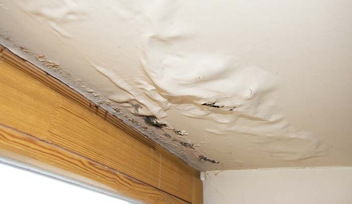 Water damaged ceiling with peeling paint and bubbles