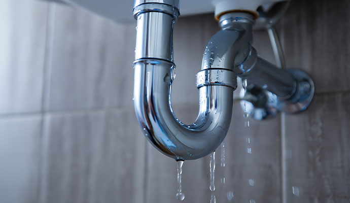 Water leaking from a p-trap plumbing pipe.